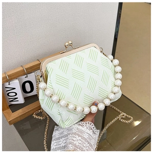 Close-up of pearl handle and metal clasp on green striped fabric frame handbag