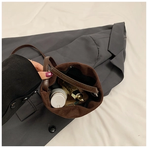 Vue de dessus de l'intérieur du sac seau en daim marron avec téléphone et cosmétiques