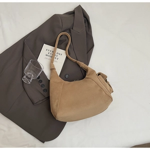 Detail of camel suede hobo bag with side pocket displayed on a grey blazer suit