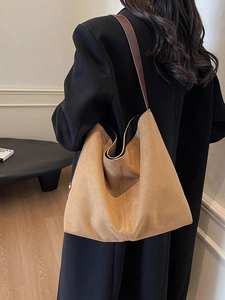 Minimalist khaki suede tote bag with brown leather strap worn by a model in soft light