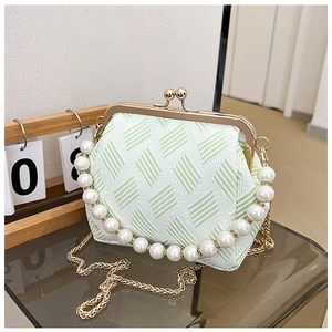 Detail of mint green textured fabric handbag with pearl handle and gold clasp