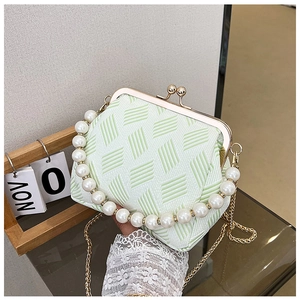 Detail of green geometric textured bag featuring pearl handle and gold chain strap
