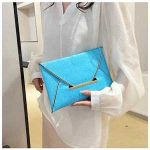 Détail de pochette enveloppe à motif étoiles et fermoir doré tenue par un mannequin