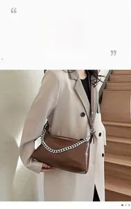Détail du sac à bandoulière en cuir brillant marron foncé avec une chaîne argentée chic
