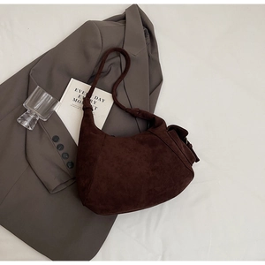 Detail of dark brown matte suede shoulder bag with retro side pleats and strap
