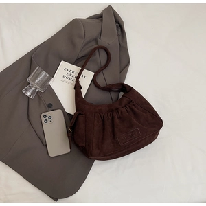 Detail of dark brown suede tote bag with ruched design and stylish long handles