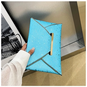 Détail de la pochette enveloppe bleue scintillante avec motif étoiles et fermoir doré chic
