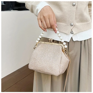 Detail of champagne gold sequin handbag with pearl handle and metal clasp closure