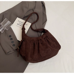 Detail of dark brown suede shoulder bag with elegant gathered design and brand label