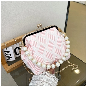 Detail of pink and white woven fabric bag with large faux pearl handle and gold clasp