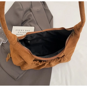 Macro view of brown suede tote bag showing metal zipper closure and black fabric lining
