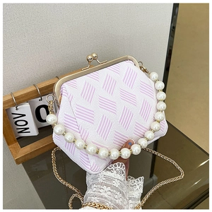 Detail of elegant pearl handle and gold chain on vintage textured crossbody bag