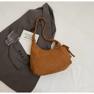 Detail view of the brown suede hobo bag texture and side zipper on white fabric