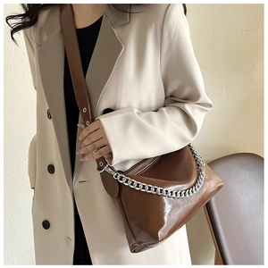 Détail d'un sac bandoulière en cuir ciré marron brillant avec chaîne en métal argenté
