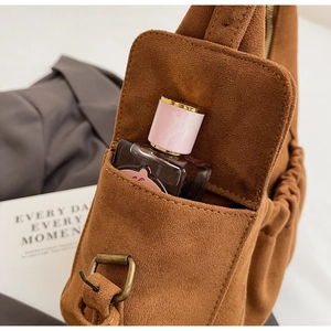 Detail view of brown faux suede tote bag featuring a side pocket with perfume bottle