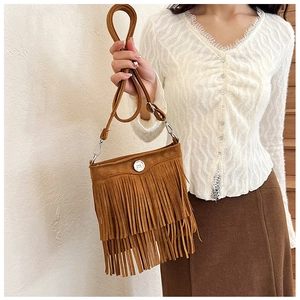 Close-up of brown suede crossbody bag with long tassels and a metal buckle detail
