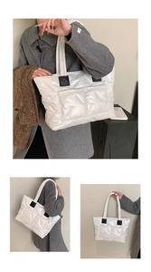 Detail of white quilted tote bag with glossy finish and black leather handle reinforcement