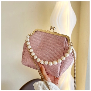Detail of pink woven clutch bag with pearl handle and golden ball clasp closure
