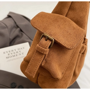 Detail of brown suede tote bag with bronze buckle and elegant vintage aesthetic