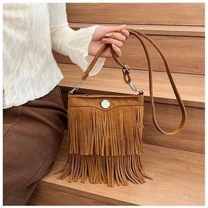 Close-up of brown suede crossbody bag with long tassels and silver metal logo buckle