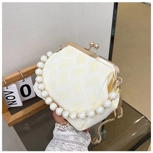 Detail of woven texture handbag with large pearl handle and gold clasp closure
