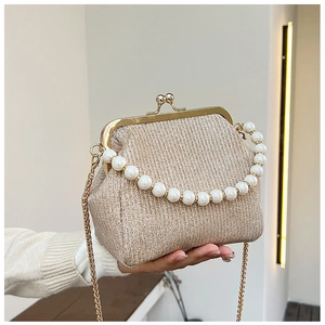 Close-up of champagne gold vintage clutch bag with large pearl handle and metal chain