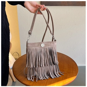 Detail showing high-quality brown suede fabric and long fringe on the crossbody bag