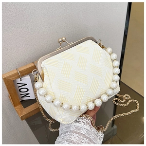 Detail of vintage cream handbag with geometric pattern, pearl handle, and gold metal clasp