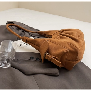 Detailed close-up of brown suede tote bag with pleats and metal buckle decoration