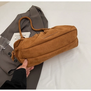 Detailed shot of brown faux suede pleated shoulder bag on grey blazer background