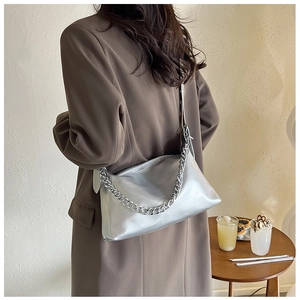 Détail d'un sac à bandoulière argenté métallisé avec chaîne épaisse sur un manteau marron
