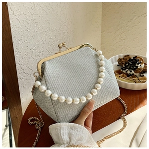 Close-up of a silver glitter evening bag with pearl handle and golden metal clasp