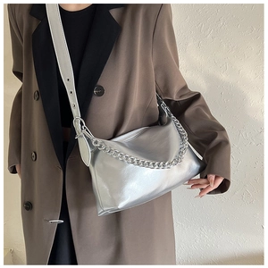 Détail du sac à bandoulière argenté avec chaîne décorative et texture métallique