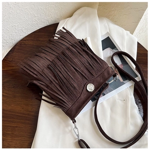 Detail of bohemian dark brown crossbody bag with long fringes and silver metal buckle