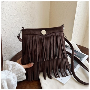 Detail showing deep brown suede crossbody bag with long tassels and silver metal lock