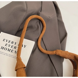 Detail view of a vintage brown suede tote bag featuring a thick curved shoulder strap and zipper