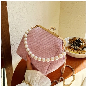 Detail of pink woven clutch bag with large pearl handle and golden metal clasp closure