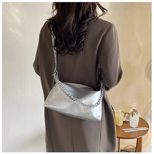 Détail du sac à bandoulière argenté avec chaîne épaisse sur l'épaule d'une femme