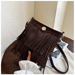 Detail of dark brown suede crossbody bag with tiered tassels and round silver buckle
