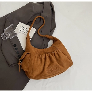 Detailed shot of brown suede tote bag featuring pleated design and embossed MKMX logo