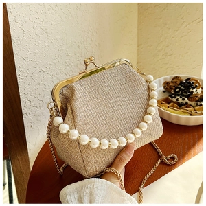 Detail of champagne gold metallic fabric bag with vintage metal frame and pearl handle