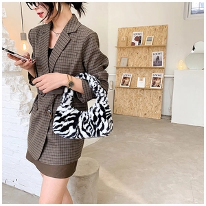 Détail d'un sac à main en peluche motif zèbre porté avec une tenue urbaine d'automne