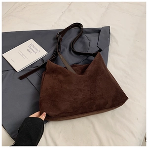 Detail of dark brown suede tote bag with adjustable leather straps on neutral background