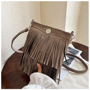 Detail of a brown suede crossbody bag with long double-layered fringe and metallic logo