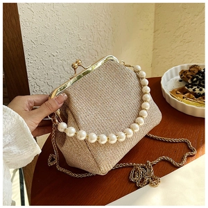 Detail of champagne gold woven handbag featuring pearl handle and vintage metal clasp