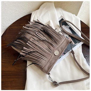 Detailed close-up of brown suede crossbody bag with long tiered tassels and metal twist lock