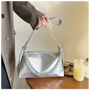 Détail d'un sac à main argenté métallisé avec chaîne épaisse sur une table de café