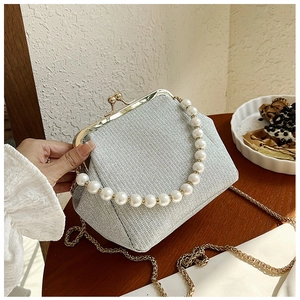 Detail of silver shimmer evening bag with pearl handle and golden chain strap