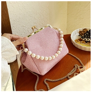 Pink tweed frame bag detail with pearl handle and golden chain on a cafe table