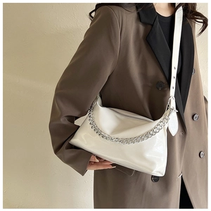 Détail d'un sac bandoulière blanc brillant avec chaîne argentée et texture souple